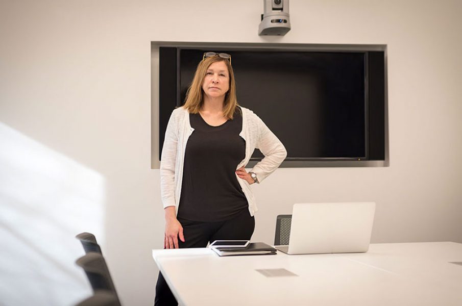 confident businesswoman standing in modern office in front of video conferencing screen